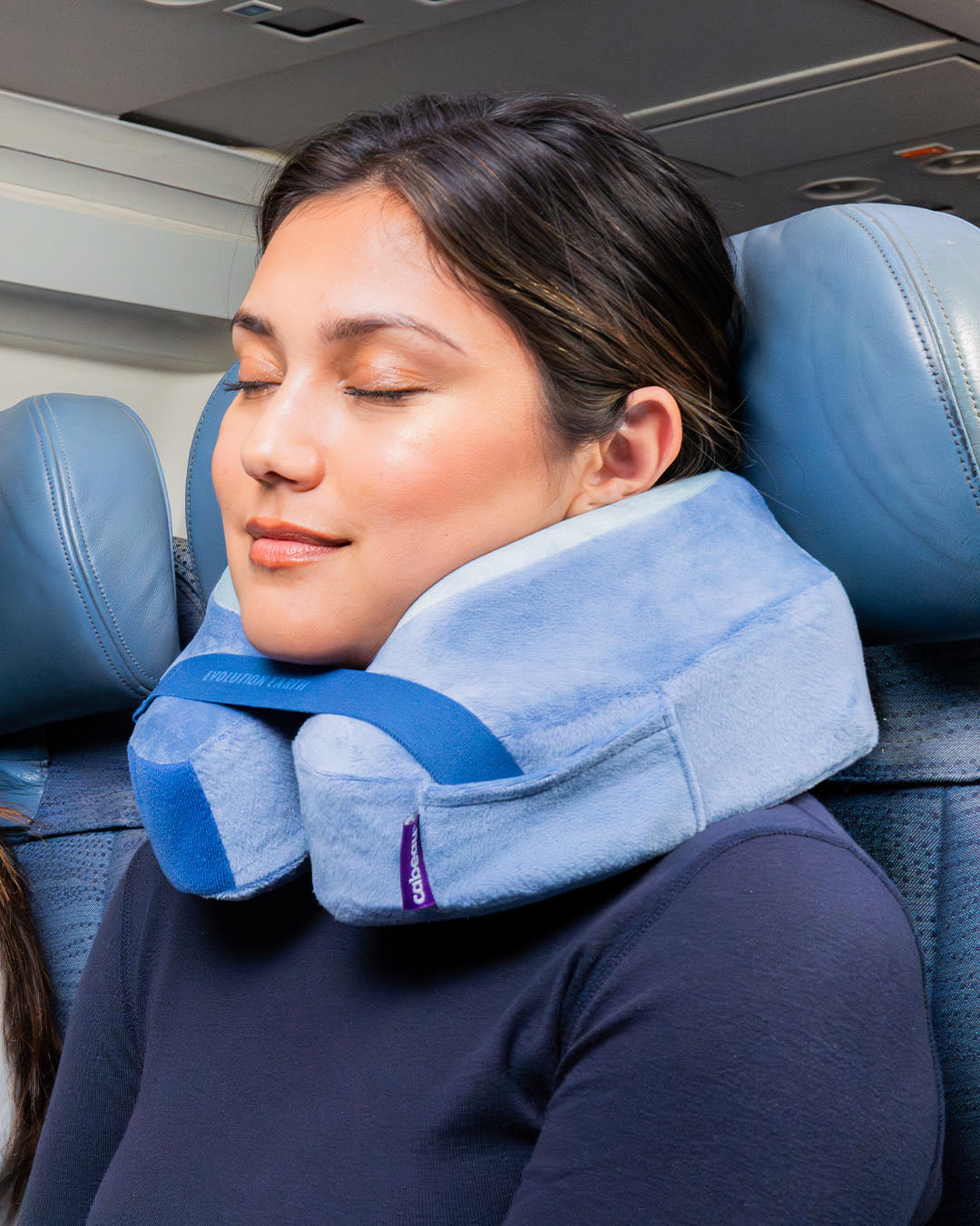 Woman using a travel neck pillow on an airplane seat