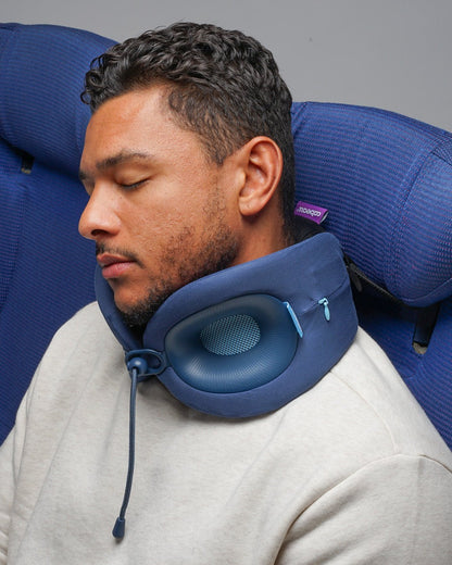 Man wearing an Evolution X neck pillow with the Head Hold S3® Seat Straps attached and strapped to a plane seat headrest - keeping the neck pillow in place 