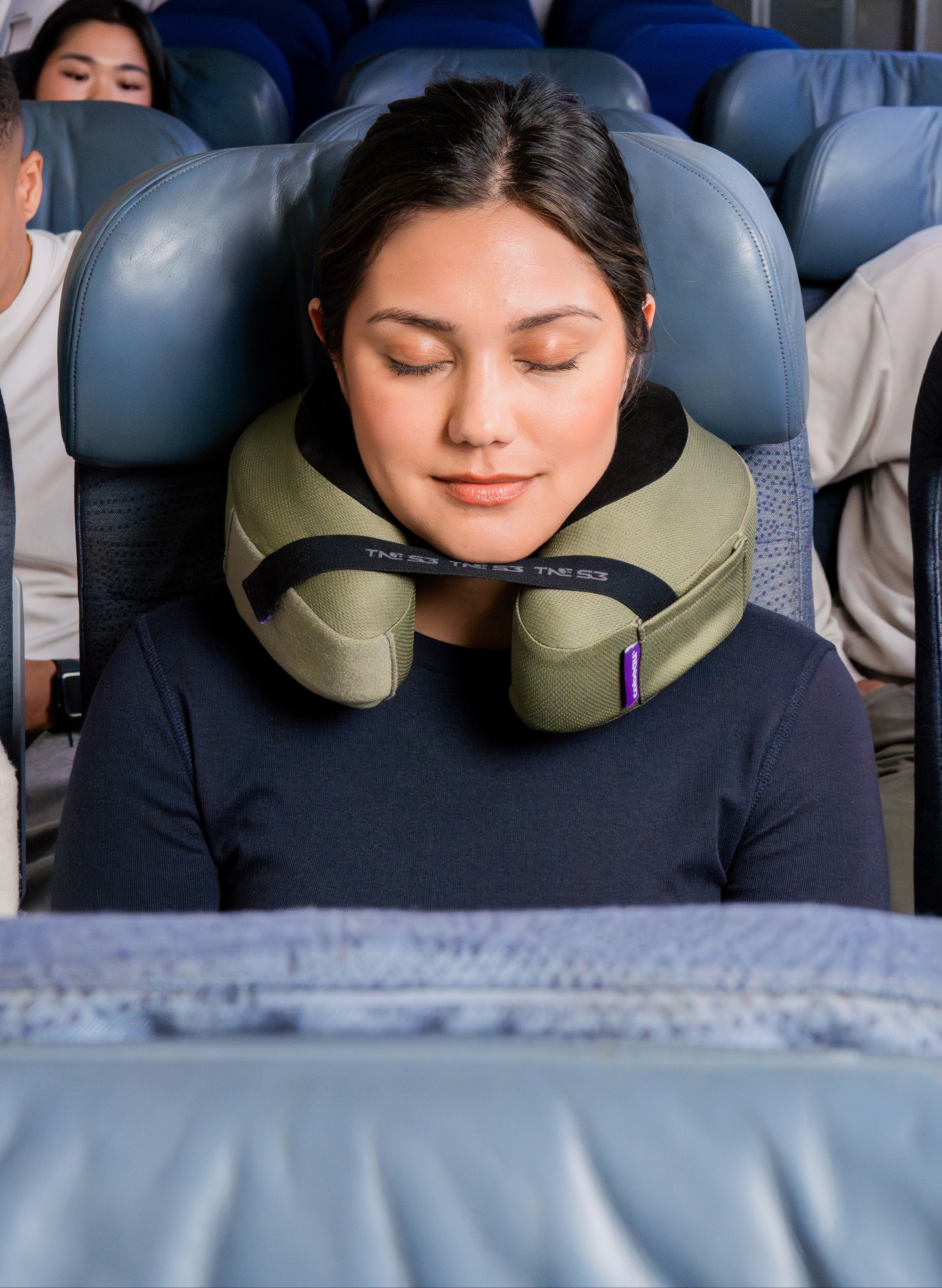 Woman using a Slim TNE Deluxe airplane neck pillow on a flight